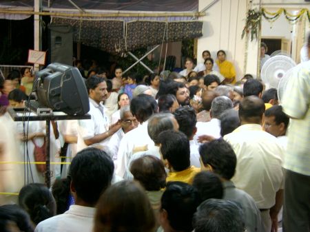 An audience of surrounds Amma, who is hugging away